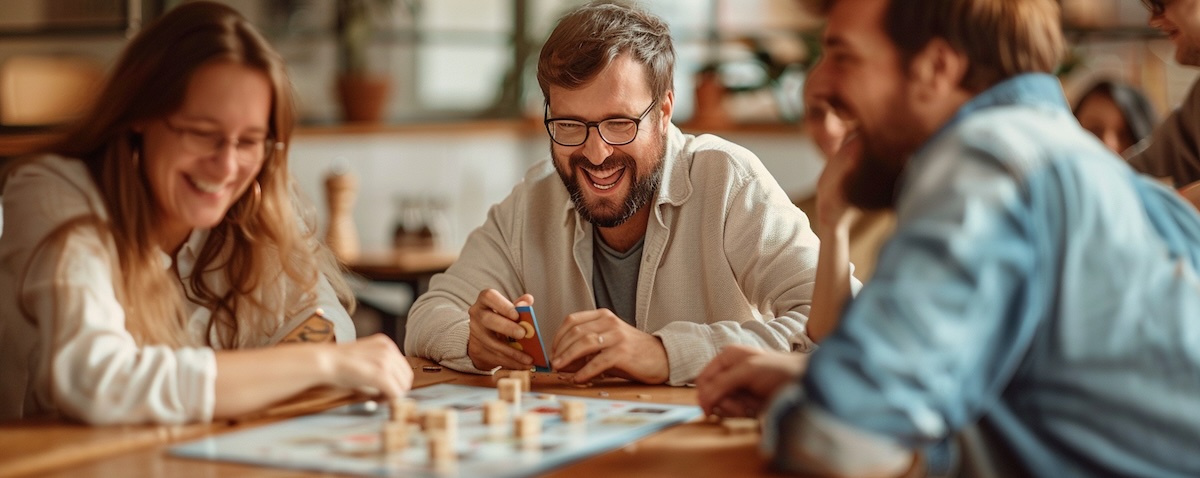 Erwachsene lernen gemeinsam Deutsch mit einem Spiel am Tisch als Symbol für spielerisches Deutschlernen