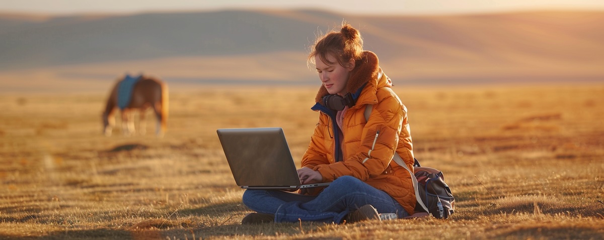 Junge Frau lernt Mongolisch am Laptop vor mongolischer Steppe mit Jurte