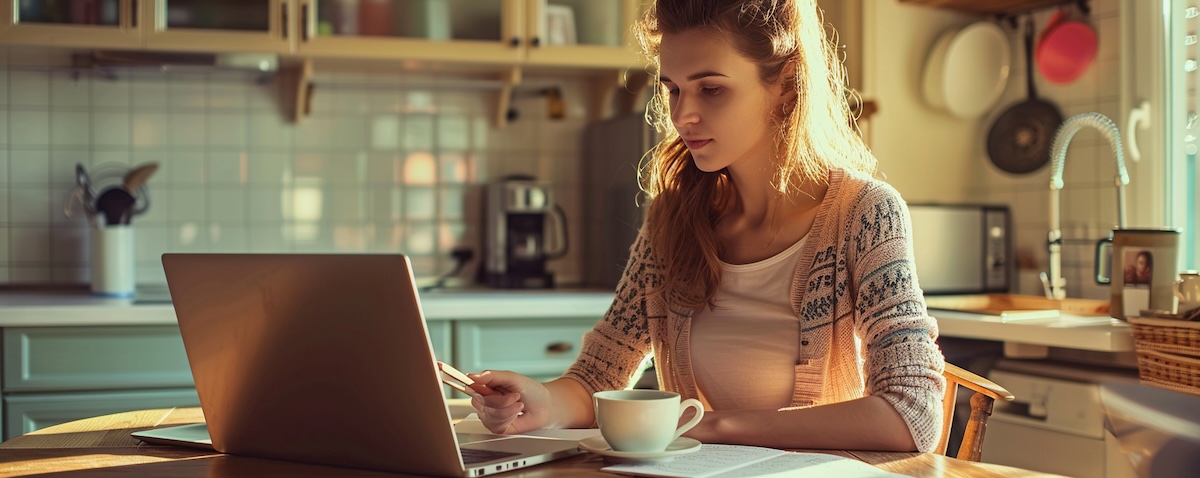 Frau lernt mit Laptop und Kaffeetasse Usbekisch am Küchentisch