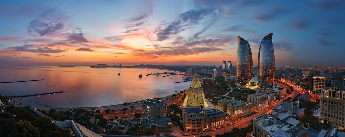 Panorama der Baku Skyline mit den beleuchteten Flame Towers am Kaspischen Meer im Abendlicht